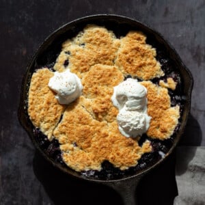 Our Vegan Blueberry Cobbler in a Cast Iron skillet over metal board