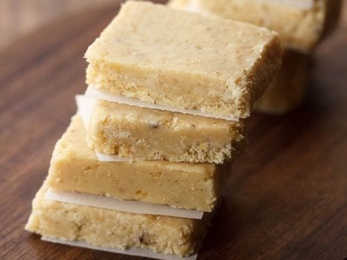 7 cup barfi stacked on a wooden board.