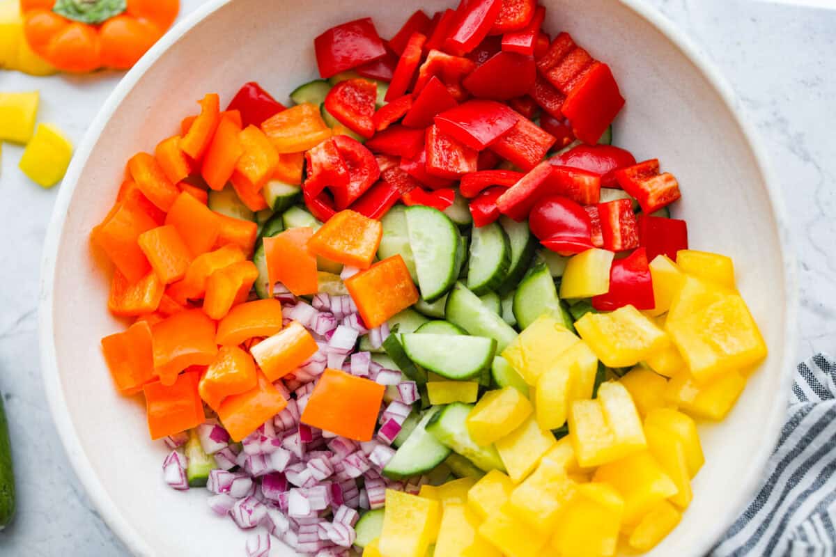 I don’t know what kind of hold cucumbers have on me lately, but I’m obsessed. This cucumber bell pepper salad is crunchy, a little sweet, a little spicy, and totally guilt-free. Bowl of chopped up vegetables.