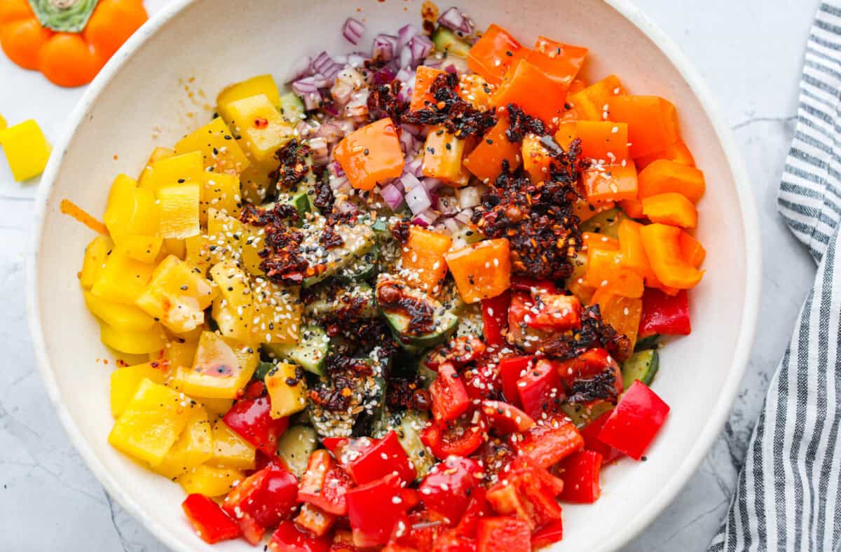I don’t know what kind of hold cucumbers have on me lately, but I’m obsessed. This cucumber bell pepper salad is crunchy, a little sweet, a little spicy, and totally guilt-free. Dressing poured over the vegetables in the bowl.
