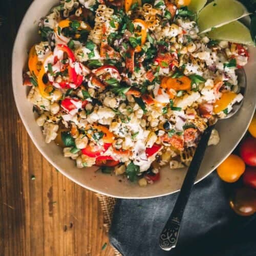 Overhead shot of a bowl of grilled corn salad with bright colorful produce and fresh herbs.