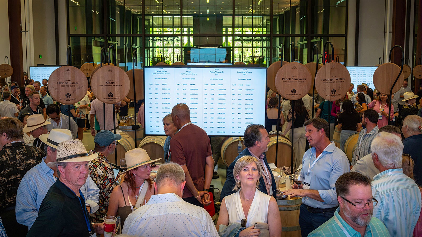 Auction Napa Valley guests at the barrel auction, with an electronic board displaying top bids