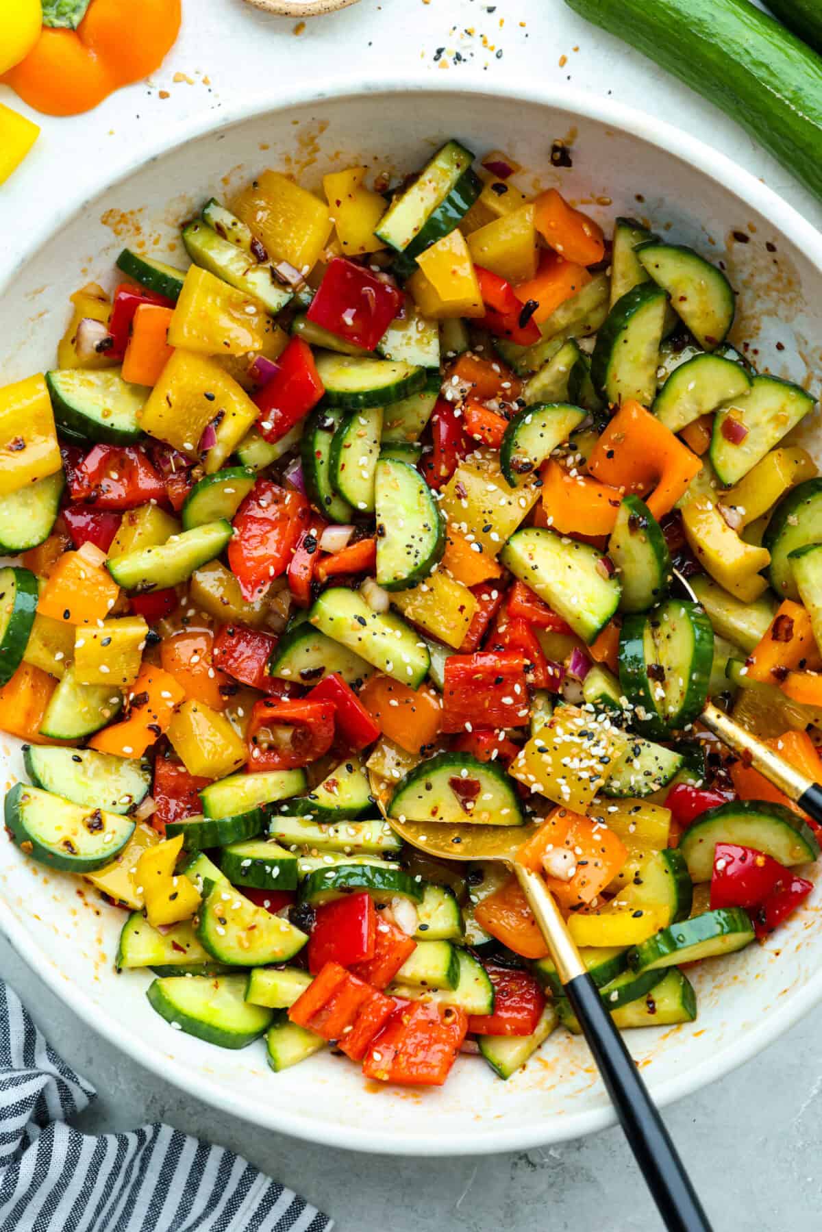 I don’t know what kind of hold cucumbers have on me lately, but I’m obsessed. This cucumber bell pepper salad is crunchy, a little sweet, a little spicy, and totally guilt-free. Crunchy cucumber and bell pepper salad in a large mixing bowl.