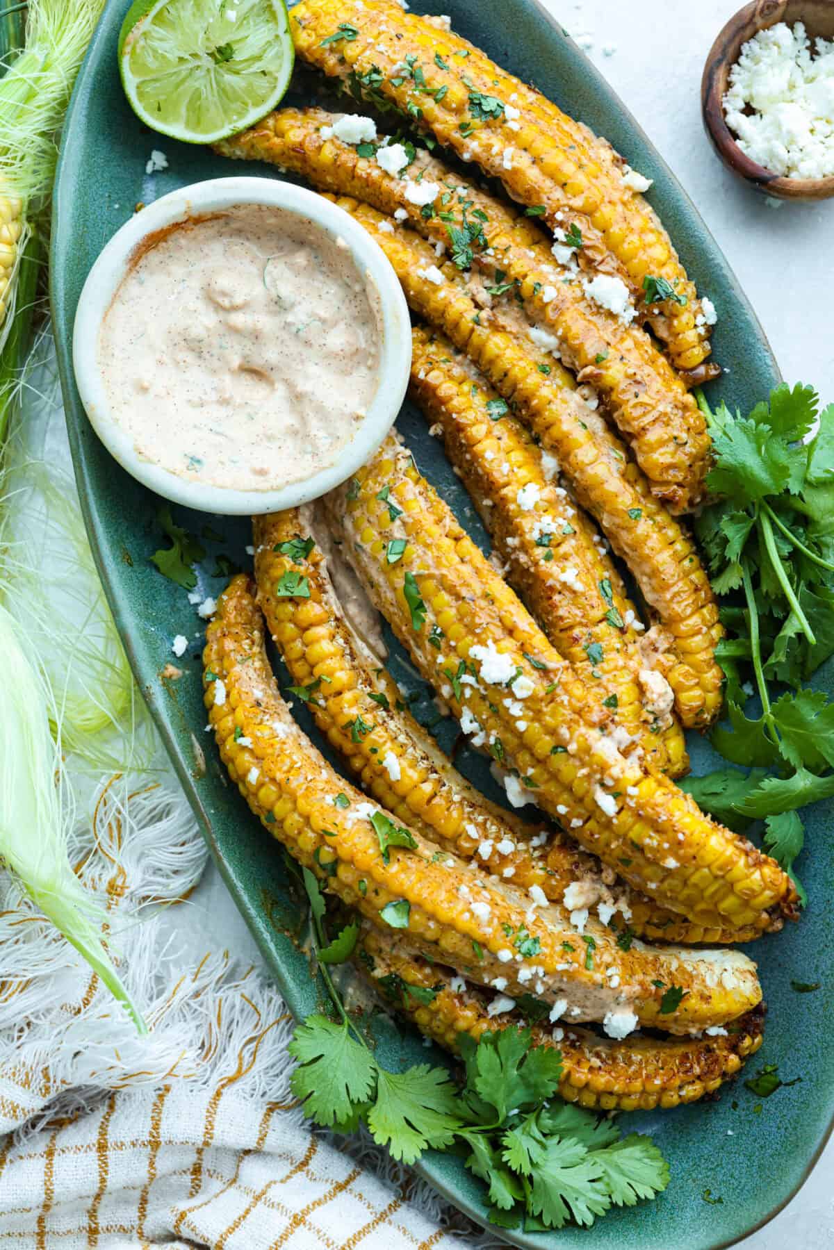 I had to try these viral Corn Ribs, and now I totally get the hype! They're fun, handheld, and smothered in creamy, zesty Mexican street corn flavor. Make a batch to share... or don’t. I won’t judge. Serving platter with cooked corn ribs smothered in Eloté sauce and garnished with Cotija cheese and cilantro.