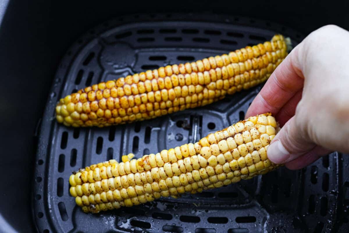 I had to try these viral Corn Ribs, and now I totally get the hype! They're fun, handheld, and smothered in creamy, zesty Mexican street corn flavor. Make a batch to share... or don’t. I won’t judge. Someone placing corn ribs into the air fryer.