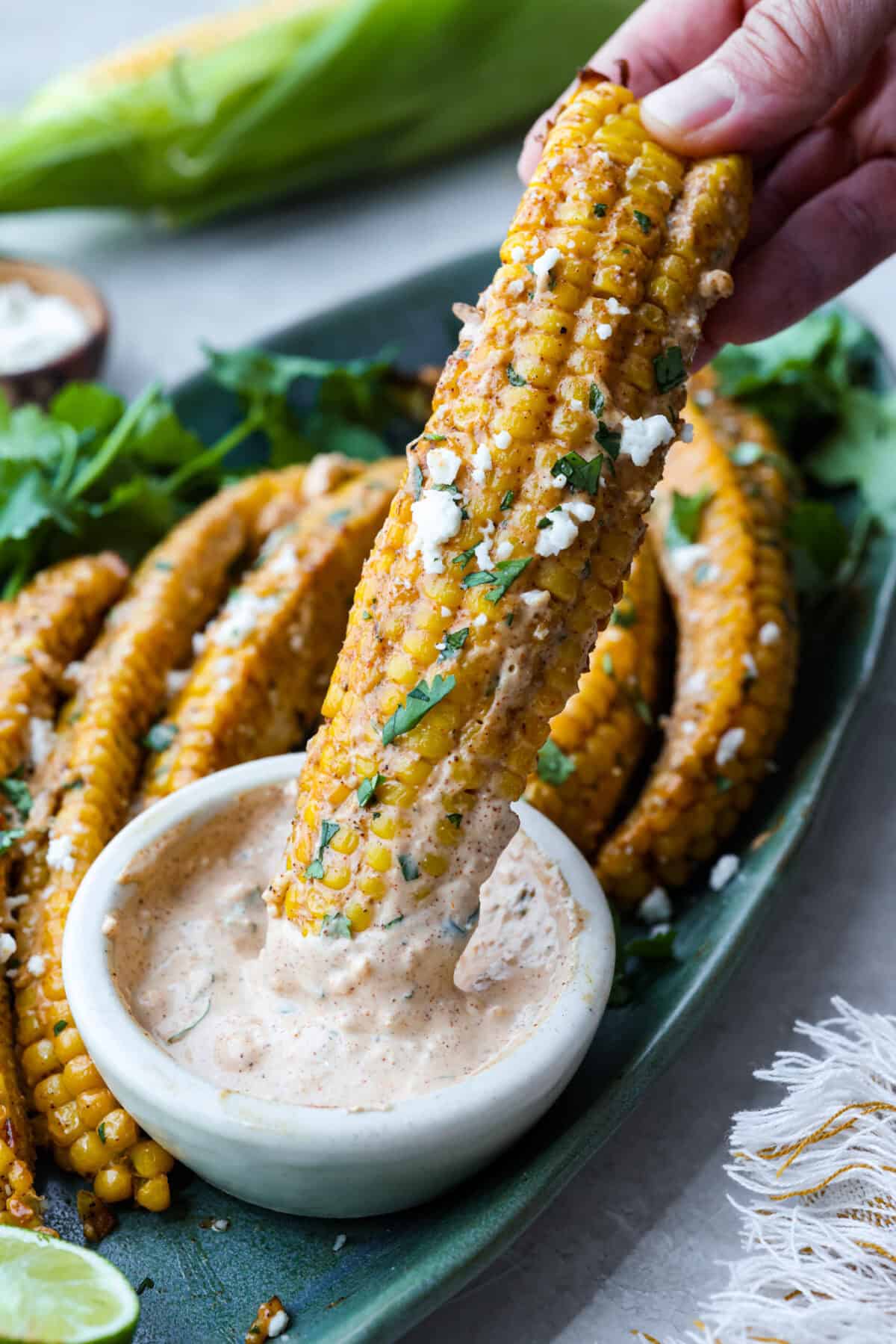 I had to try these viral Corn Ribs, and now I totally get the hype! They're fun, handheld, and smothered in creamy, zesty Mexican street corn flavor. Make a batch to share... or don’t. I won’t judge. Someone dipping a corn rib into the elote sauce.
