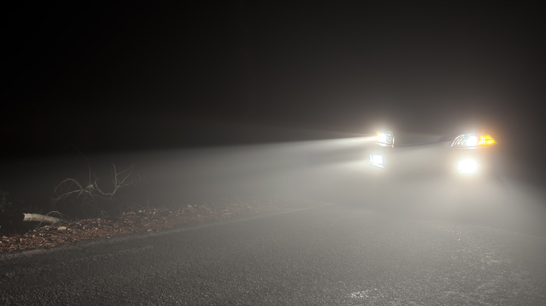 Car with both headlights and fog lights on in the night.