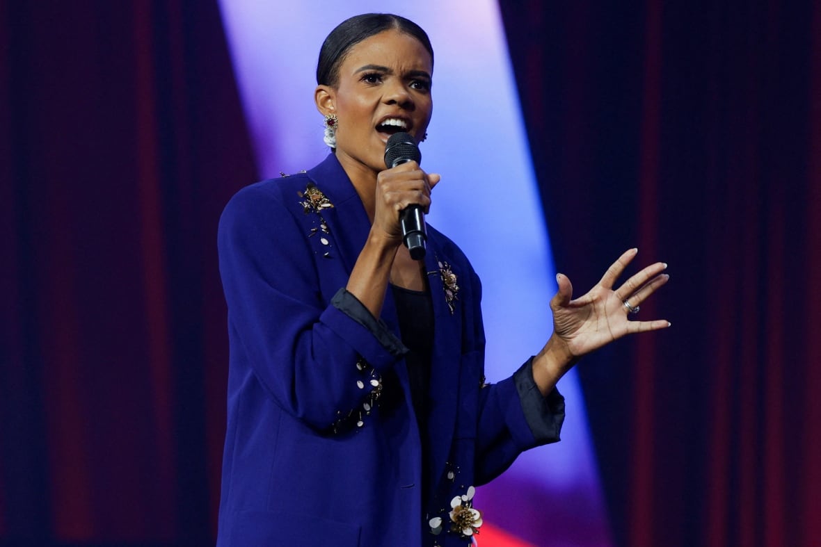 Woman with black hair wearing a blue suit speaks into a microphone