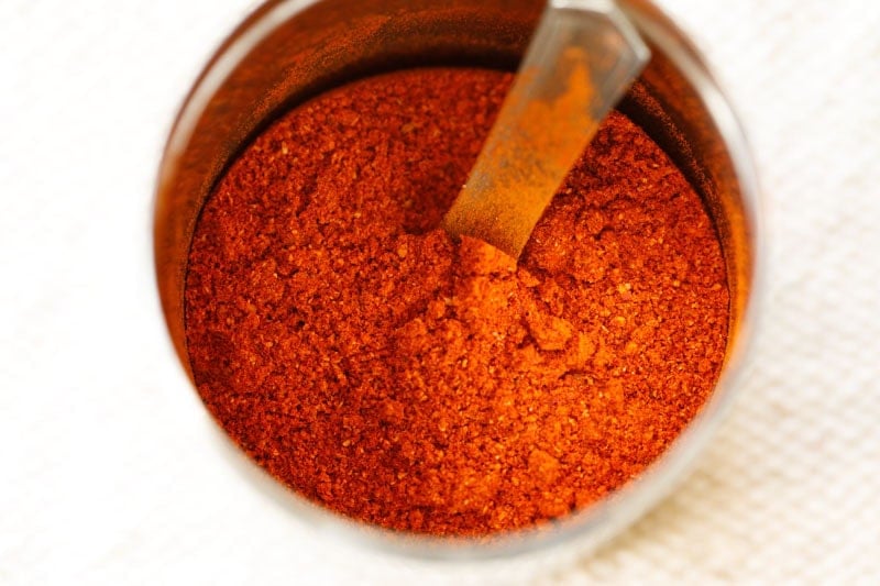 homemade red chilli powder in a spice steel jar with a spoon. 