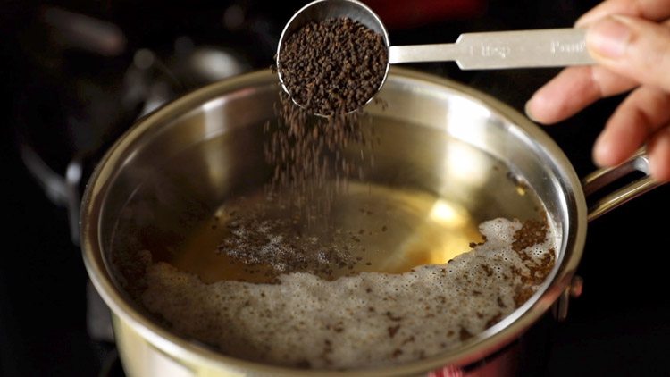 adding black tea powder to boiling water.