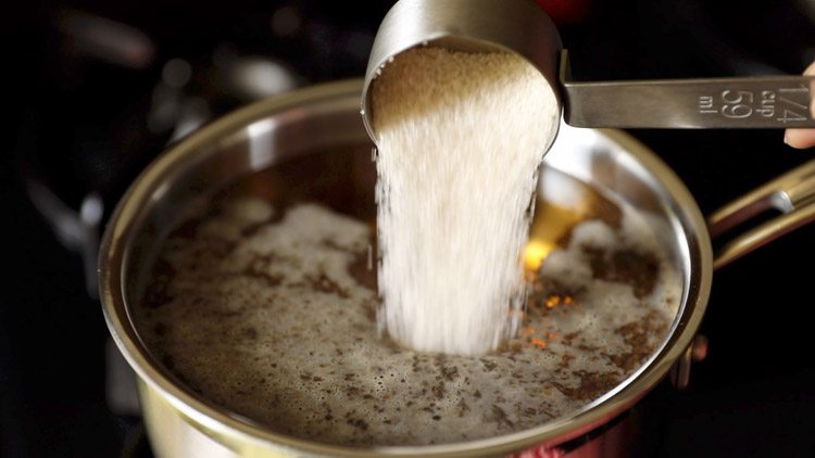 adding sugar to boiling water.