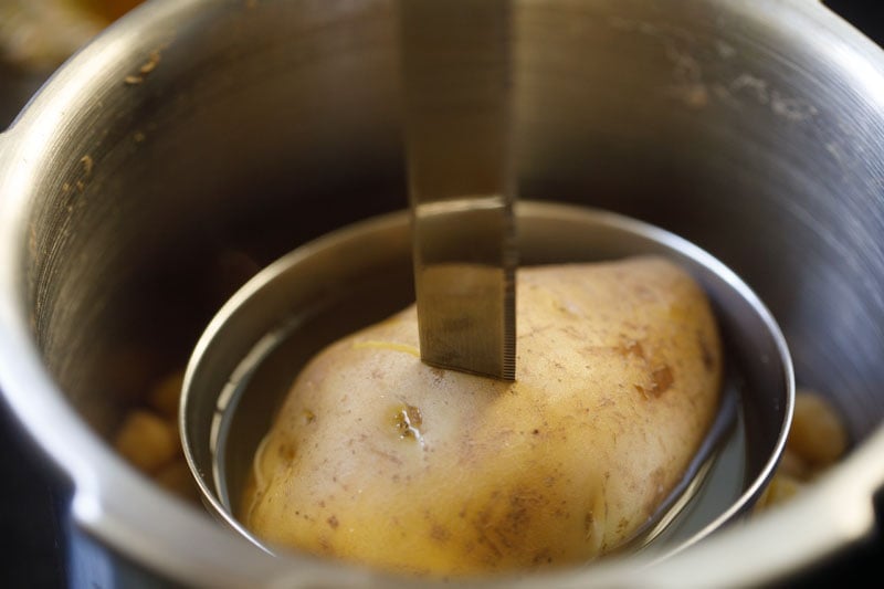 checking cooked potato with a knife. 