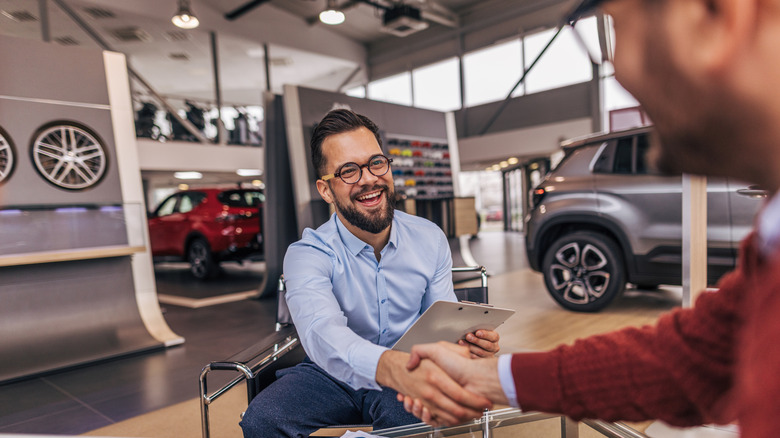 A car salesperson shaking hands with a customer